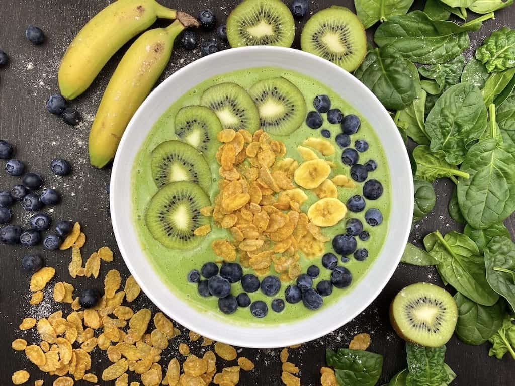 Smoothie Bowl mit verschiedenen Toppings: Banane, Beern, Cornflakes und Kiwi